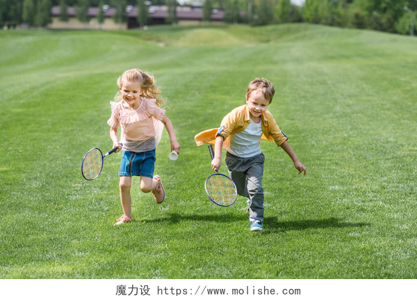 可爱的儿童拿羽毛球拍一起在公园跑可爱的微笑儿童与羽毛球球拍一起跑在公园 